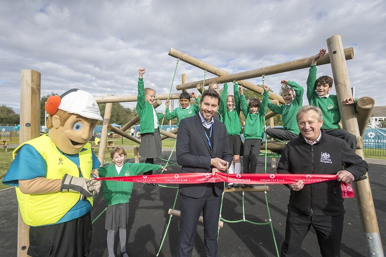 An image showing a ribbon being cut for the opening of the play area on Maple Drive.